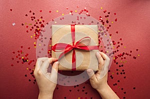 Gift box tied with red ribbon on pastel pink background.