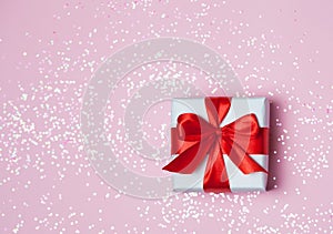 Gift box vith red bow and glitter sparkles on pink background. st. Valentine`s day concept