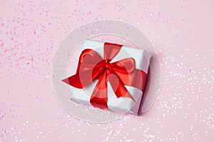 Gift box vith red bow and glitter sparkles on pink background. st. Valentine`s day concept