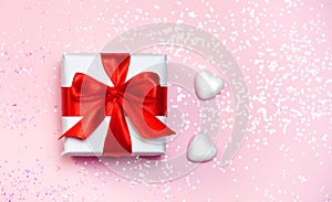 Gift box vith red bow and glitter sparkles on pink background. st. Valentine`s day concept