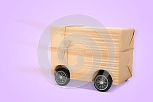 Gift box on wheels against pale violet background. Order hurrying to client. Delivery service