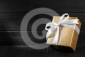 Gift box with ribbon on black wooden background top view.