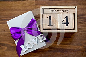 Gift box on the wooden background with violet ribbon. Valentine`s Day gift.