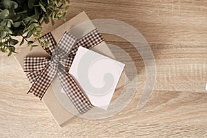 Gift box on wooden table with blank paper for text