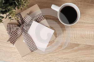 Gift box on wooden table with blank paper for text and coffee