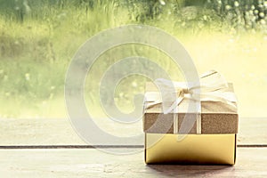 Gift box on wooden table on rainy day window background