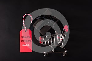 Gift box wrapped black paper and black bow ribbon present in the shopping cart and red tag label