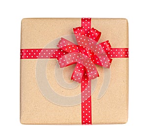 Gift box wrapped in brown recycled paper with red polka dot ribbon bow top view isolated on white background, clipping path