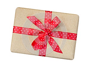 Gift box wrapped in brown recycled paper with red polka dot ribbon bow top view isolated on white background, clipping path