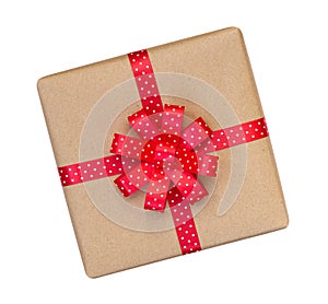 Gift box wrapped in brown recycled paper with red polka dot ribbon bow top view isolated on white background, clipping path