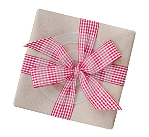 Gift box wrapped in brown recycled paper with red and white gingham ribbon bow top view isolated on white background, clipping pa