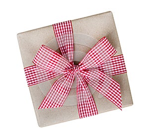 Gift box wrapped in brown recycled paper with red and white gingham ribbon bow top view isolated on white background, path