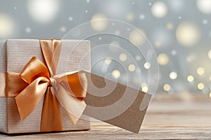 Gift box wrapped with craft paper and bow on neutral background with boke. Holiday concept