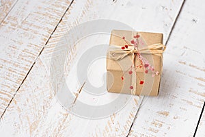 Gift box wrapped in craft paper tied with twine, tender small red flower, top view