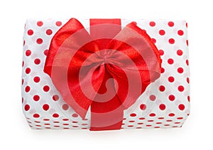 Gift box wrapped in white paper with red dots and bright red ribbon bow. Isolated on a white background, top view