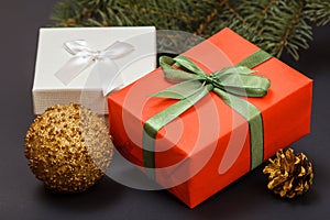 Gift boxes, ball, cone and fir tree branch on black background