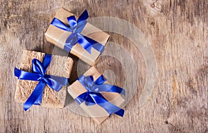 Gift boxes with blue ribbons on the old wooden background. Copy space.