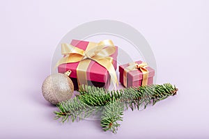 Gift boxes, Christmas ball and spruce branch on light purple background. Winter holidays, festive background