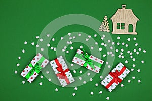 Gift boxes and Christmas wooden toys on a green background. Snowy background for Christmas cards. View from above. Copy space
