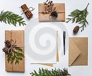 Gift boxes in craft paper and a letter on white background. Christmas or other holiday concept, top view, flat lay
