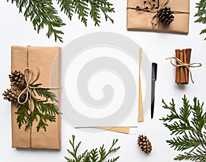 Gift boxes in craft paper and a letter on white background. Christmas or other holiday concept, top view, flat lay