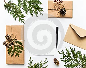 Gift boxes in eco paper and a letter on white background. Christmas or other holiday concept, top view, flat lay