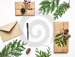 Gift boxes in eco paper and a letter on white background. Christmas or other holiday concept, top view, flat lay