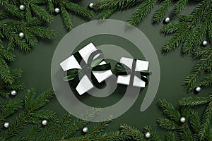 Gift boxes, fir branches and silver baubles on a green background. Christmas gifts. Happy new year. Christmas shopping concept.