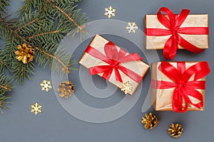Gift boxes, fir tree branches with cones on gray background