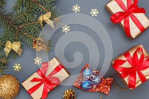 Gift boxes, fir tree branches with cones and toys on gray background