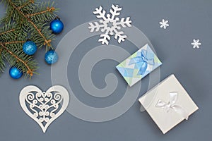 Gift boxes, fir tree branches with toy balls, snowflackes on gray background