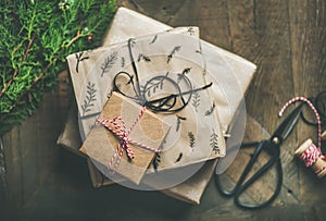 Gift boxes, fur tree branches, rope, scissors over wooden background