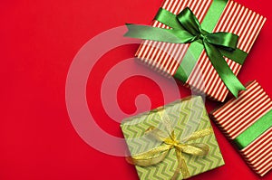 Gift boxes with green ribbon on red background top view flat lay. Holiday concept, new year or Christmas gift box, presents Xmas h