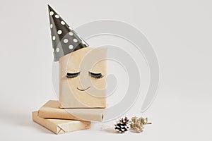 gift boxes with kraft paper on gray background, original gift decor with false eyelashes and party hat, minimalistic