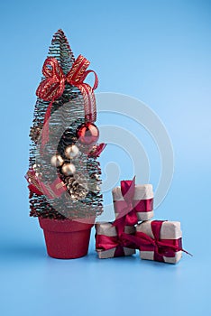 Gift boxes made of craft paper with red ribbons on a blue background. Christmas tree