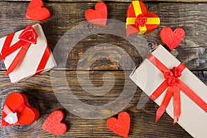 Gift boxes papier mache in the form of red hearts tied with satin ribbons and gifts Packed by craft paper on the wooden table.