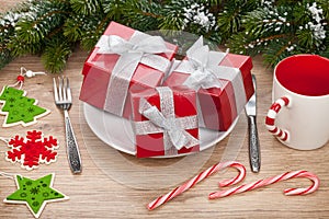 Gift boxes on plate, fir tree and christmas decor