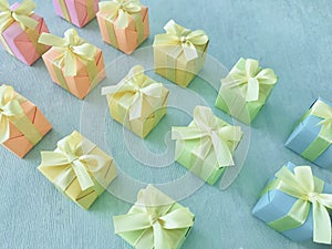 Gift boxes with rainbow light gradient colors are neatly arranged diagonally on a blue-green watercolor textured background.