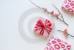 Gift boxes with red bow, lipstick kisses and quince flowers on the white background. Valentine\'s day concept frame.