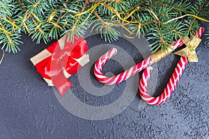 Gift boxes with red bows, caramel sticks and fir branches on concrete background. Copy space. Christmas and New Year concept.