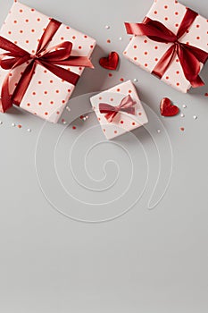 Gift boxes with red ribbon bow and heart shaped candy on gray background