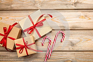 Gift boxes with red ribbon and candy canes on wooden background, copy space, top view