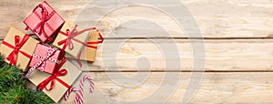 Gift boxes with red ribbons and candy canes on wooden background, banner, copy space, top view