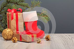 Gift boxes, Santa`s boot and fir tree branch on gray background