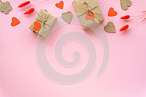 Gift boxes wrapped in craft paper with hearts and spikelets on pink background