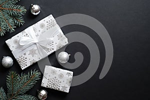 Gift boxes wrapped silver paper and fir tree branches with decorative balls over black background. Christmas banner mockup, New