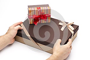 Gift boxes are wrapped up by tapes in hands on a white background.