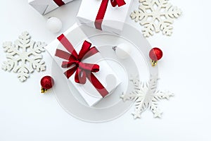 Gift boxes wrapped white paper and red ribbon decorated bubles and snowflakes on white background. Top view. Flat lay.  Christmas