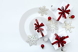 Gift boxes wrapped white paper and red ribbon decorated bubles and snowflakes on white background. Top view. Flat lay.  Christmas