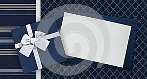 Gift card and gift box with ribbon and bow isolated on elegant blue fabrics background, top view and copy space template, useful